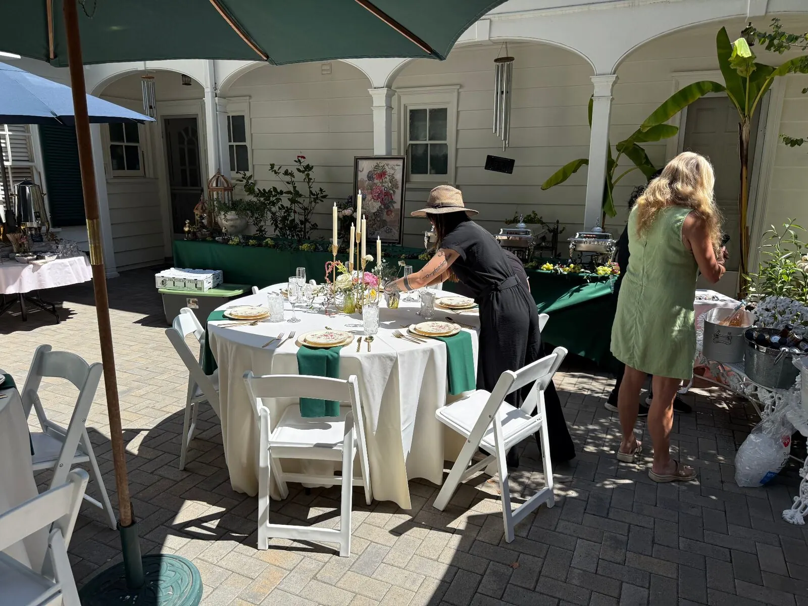 Courtyard rounds in emerald linens finished with compact centerpieces, stemware and full place settings — floral and rental styling from Menlo Park catering