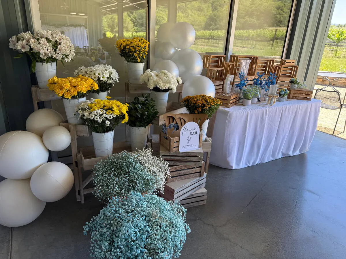 Bloom bar stocked with yellow roses, daisies and baby's breath alongside ribbon and paper for guests to wrap their own bouquets — bloom bar experience from Belmont catering