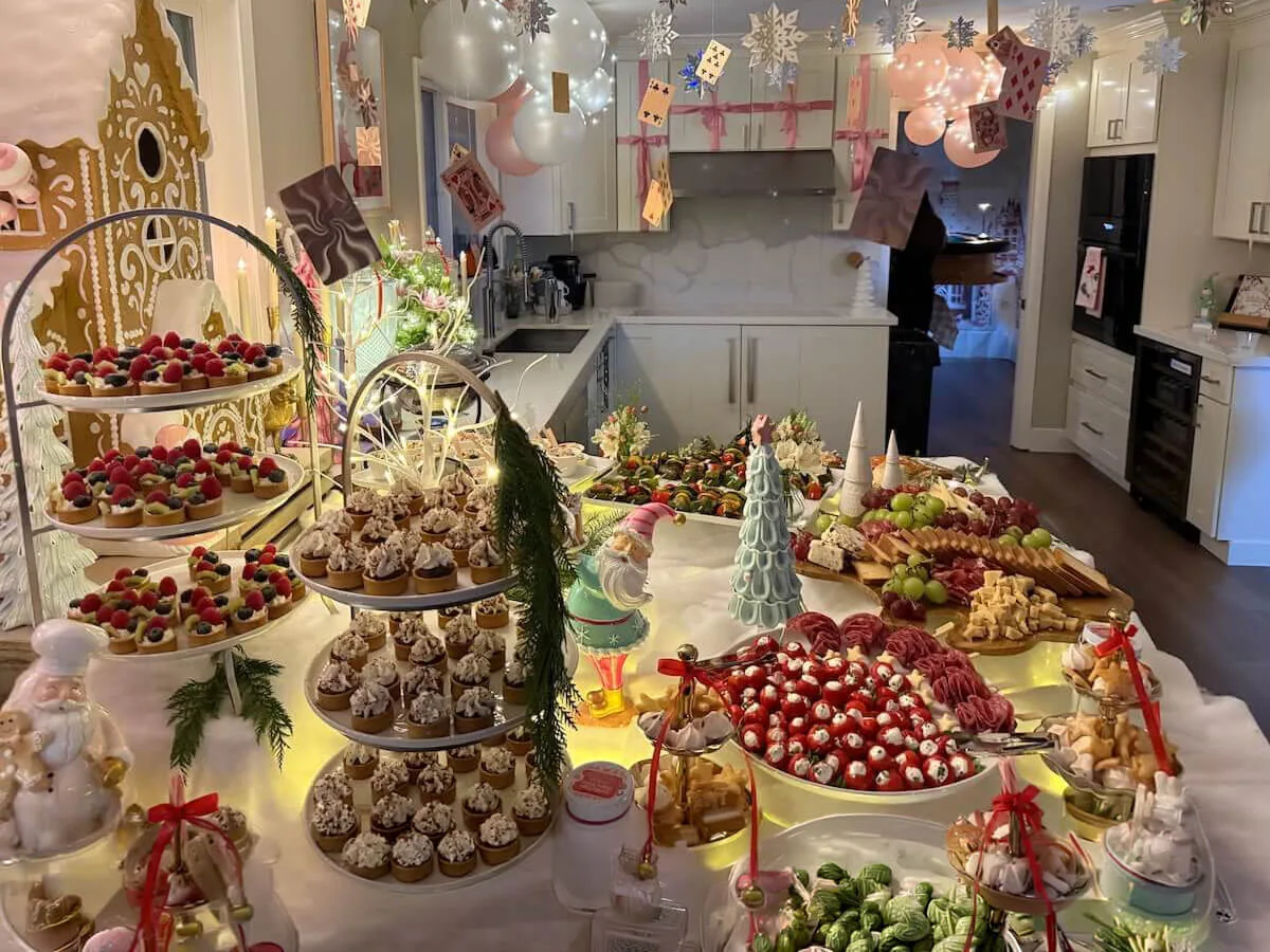 Themed party tablescape where tiered tarts and cupcakes sit beneath pastel balloons with fresh blossom accents tucked in — floral party styling for Foster City catering celebrations