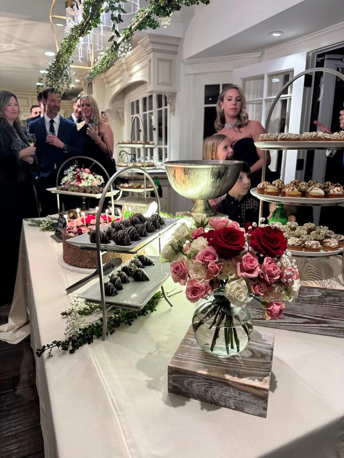 Wedding dessert display with tiered cake, mini pastries and chocolate-dipped strawberries at a Redwood City reception by Winslow's Catering Redwood City