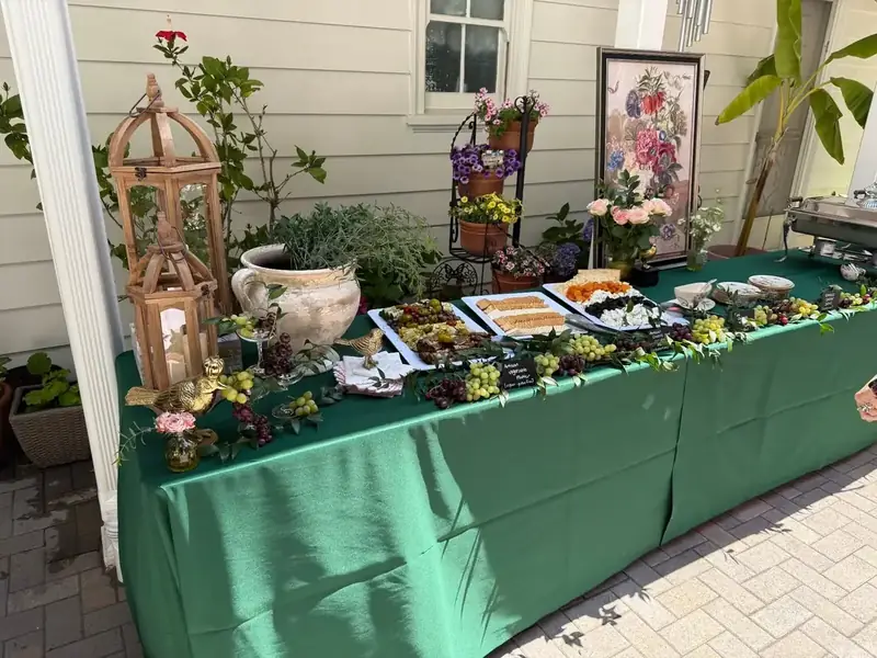 Winslow’s Catering Redwood City garden buffet arranged with artisan snacks, grape clusters, fresh blooms, and vintage decorative pieces.